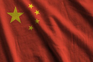 Stüdyo ışıklarının altında büyük kıvrımlı Çin bayrağı sallanıyor. Resmi semboller ve renkler kumaş pankartıyla