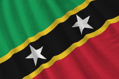 Saint Kitts ve Nevis bayrağı. Stüdyo ışıklarının altında büyük kıvrımlar sallanıyor. Resmi semboller ve renkler kumaş pankartıyla