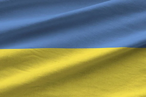 Ukraine flag with big folds waving close up under the studio light indoors. The official symbols and colors in fabric banner