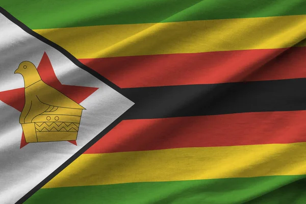 Zimbabwe flag with big folds waving close up under the studio light indoors. The official symbols and colors in fabric banner
