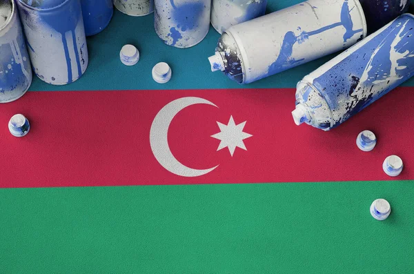 Azerbaijan flag and few used aerosol spray cans for graffiti painting. Street art culture concept, vandalism problems