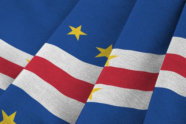 Cabo verde flag with big folds waving close up under the studio light indoors. The official symbols and colors in fabric banner