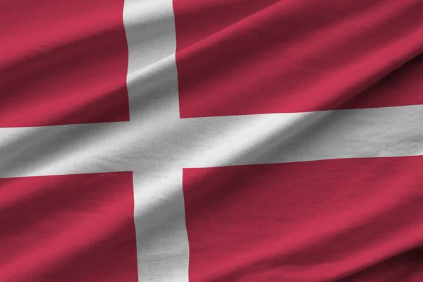 Denmark flag with big folds waving close up under the studio light indoors. The official symbols and colors in fabric banner