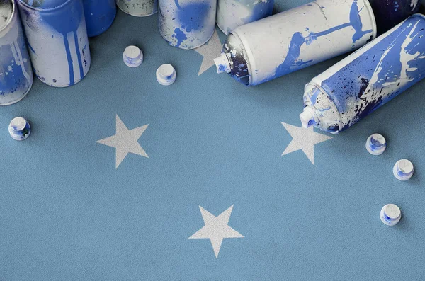 Micronesia flag and few used aerosol spray cans for graffiti painting. Street art culture concept, vandalism problems