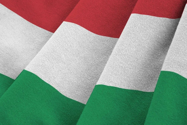Hungary flag with big folds waving close up under the studio light indoors. The official symbols and colors in fabric banner