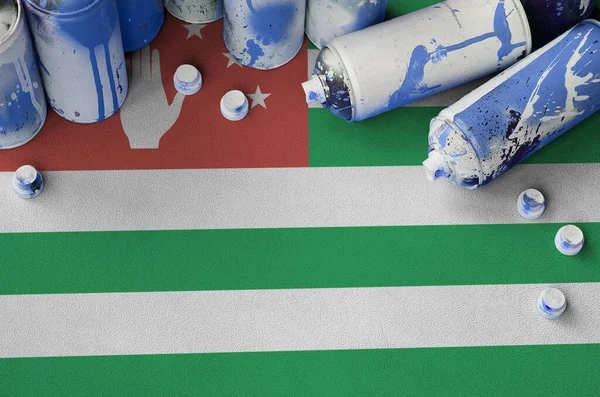 Abkhazia flag and few used aerosol spray cans for graffiti painting. Street art culture concept, vandalism problems