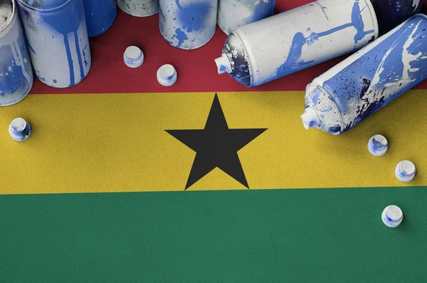 Ghana flag and few used aerosol spray cans for graffiti painting. Street art culture concept, vandalism problems
