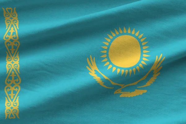 Kazakhstan flag with big folds waving close up under the studio light indoors. The official symbols and colors in fabric banner