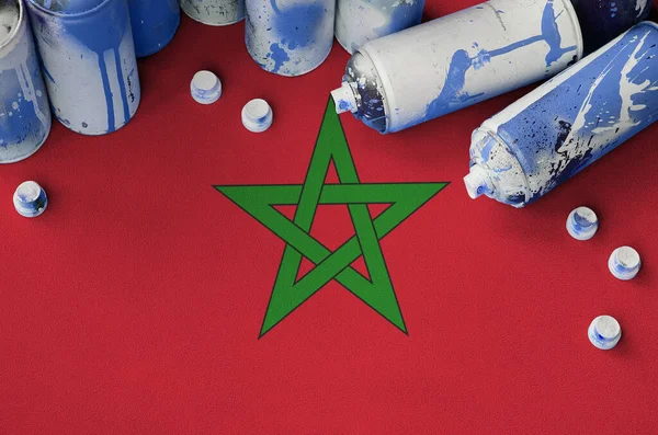 Morocco flag and few used aerosol spray cans for graffiti painting. Street art culture concept, vandalism problems