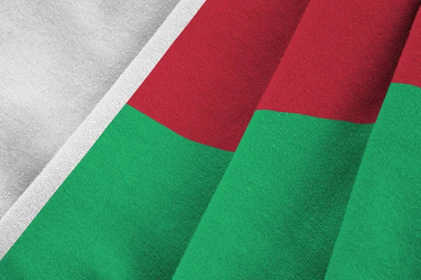 在室内的演播室灯光下 巨大的褶皱摇曳着马达加斯加国旗 织物横幅中的官方符号和颜色 — 图库照片