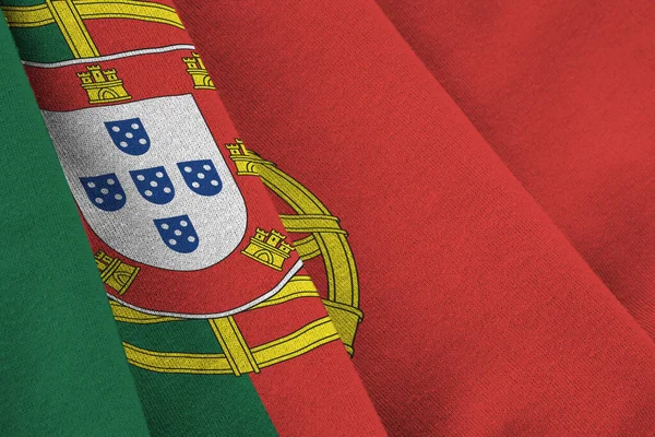 スタジオライトの下に大きな折り目の付いたポルトガルの旗が屋内で手を振っている ファブリックバナーの公式シンボルと色 — ストック写真