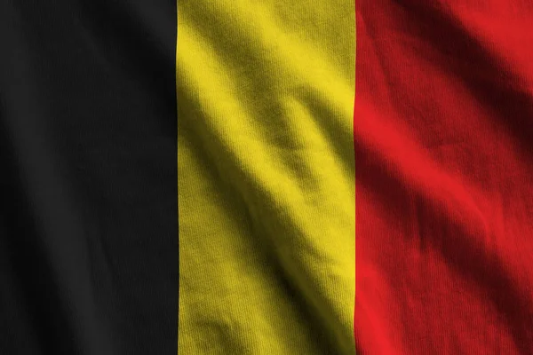 スタジオライトの下で大きな折り目の付いたベルギーの旗が屋内で手を振っています ファブリックバナーの公式シンボルと色 — ストック写真