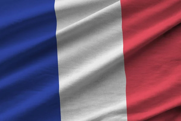 France flag with big folds waving close up under the studio light indoors. The official symbols and colors in fabric banner