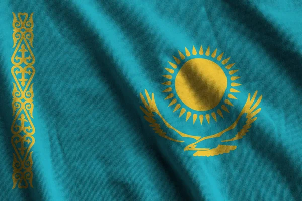 Kazakhstan flag with big folds waving close up under the studio light indoors. The official symbols and colors in fabric banner