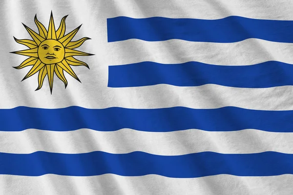 ウルグアイの国旗で 大きな折り目がスタジオの光の下で屋内で手を振っている ファブリックバナーの公式シンボルと色 — ストック写真