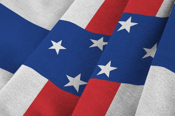 Netherlands Antilles flag with big folds waving close up under the studio light indoors. The official symbols and colors in fabric banner