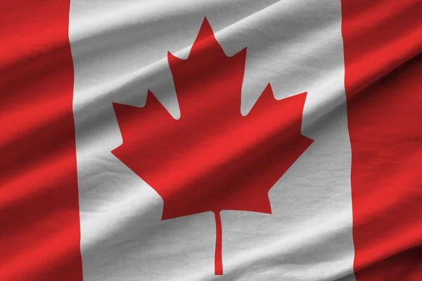 Canada flag with big folds waving close up under the studio light indoors. The official symbols and colors in fabric banner