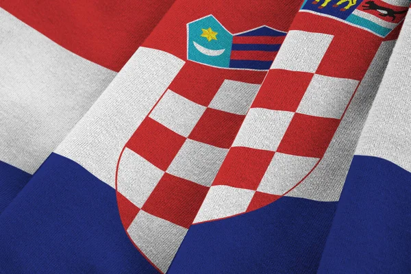 Croatia flag with big folds waving close up under the studio light indoors. The official symbols and colors in fabric banner