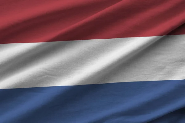 Netherlands flag with big folds waving close up under the studio light indoors. The official symbols and colors in fabric banner