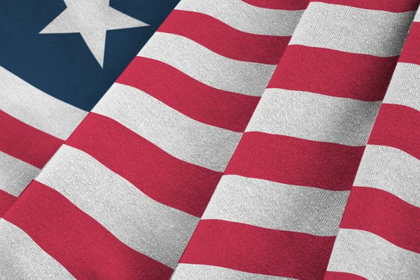 Liberia flag with big folds waving close up under the studio light indoors. The official symbols and colors in fabric banner