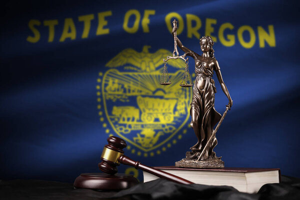 Oregon US state flag with statue of lady justice, constitution and judge hammer on black drapery. Concept of judgement and punishment