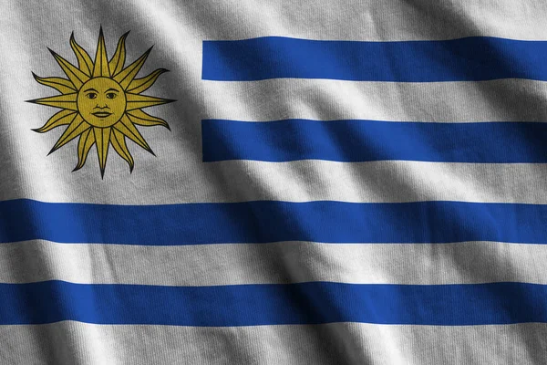 ウルグアイの国旗で 大きな折り目がスタジオの光の下で屋内で手を振っている ファブリックバナーの公式シンボルと色 — ストック写真