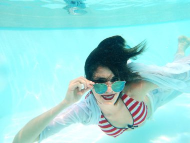 Havuz başında güneş gözlüklü güzel bir kadın portresi.