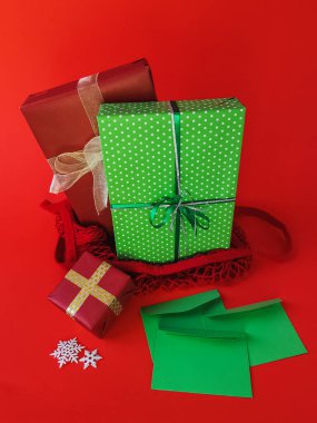 Kırmızı arka planda Noel ve yeni yıl hediyeleri ve tatil süslemeleri. Kırmızı arkaplanı olan kutlama kartı, Noel ağacı süslemeleri, kartpostal için tatil süslemeleri.