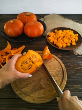 Portakal rengi küçük balkabakları ahşap bir tahtada yemek tarifleri ve karanlık bir masada parçalara ayırmak için.