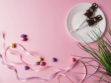 Kartlı Paskalya kompozisyonu ve tebrik kartları, çikolatalı tavşanlar, pembe arka plan, çok renkli, soluk pembe arka planda paskalya yumurtaları, Paskalya süslemeleri, kurdeleler, şekerler