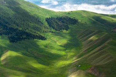 Dağların yeşil yamaçlarında, bulutların gölgesi yerde yatıyor..