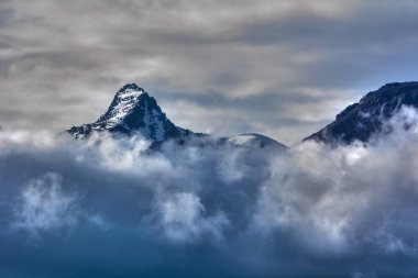 Bulutların arasındaki karlı dağ zirveleri, Kırgız sırtı, Chonkurchak yolu, Kırgızistan ülkesi.