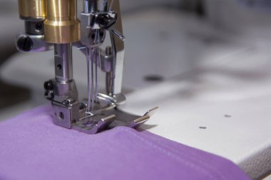 Terzi dikiş makinesine kumaş dikiyor.