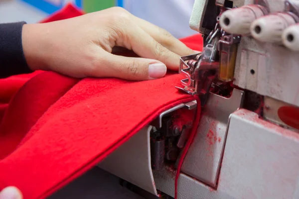 Terzi dikiş makinesine kumaş dikiyor.