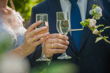 Gelin ve damat ellerinde şampanya kadehleri tutuyorlar.