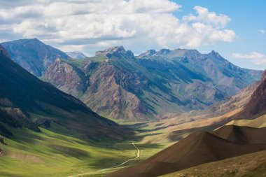 Dağların yeşil yamaçlarında, bulutların gölgesi yerde yatıyor..