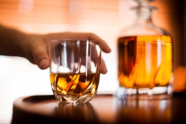 İnsan eli, viski bardağı karanlık bir bar ortamında kapanıyor. Bardağa odaklan. Boşluğu kopyala. Yüksek kalite fotoğraf