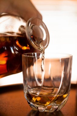 İnsan eli, viski bardağı karanlık bir bar ortamında kapanıyor. Bardağa odaklan. Boşluğu kopyala. Yüksek kalite fotoğraf