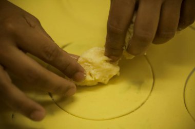 İnsan elleri mutfak masasında çiğ ve kuru kapeletti makarnası yapıyor.