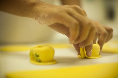 İnsan elleri mutfak masasında çiğ ve kuru kapeletti makarnası yapıyor.