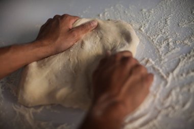 İnsan eli makarna yapıyor. Mutfak masasında çiğ ve kuru makarna yapıyor.