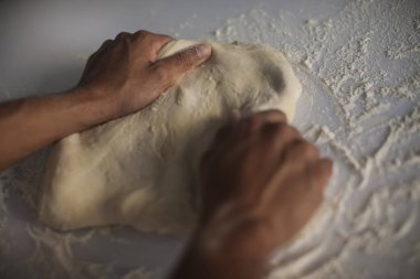 İnsan eli makarna yapıyor. Mutfak masasında çiğ ve kuru makarna yapıyor.