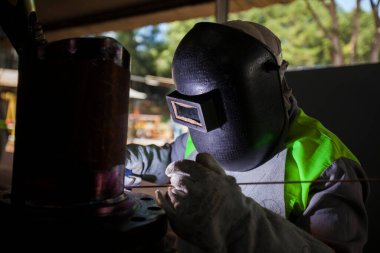 İnsan kaynak yapmak için elektrikli kaynak makinesi kullanarak metal kaynaklama çeliği üzerinde çalışır..