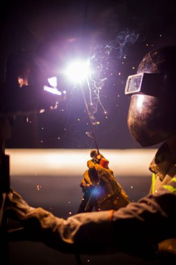 İnsan kaynak yapmak için elektrikli kaynak makinesi kullanarak metal kaynaklama çeliği üzerinde çalışır..