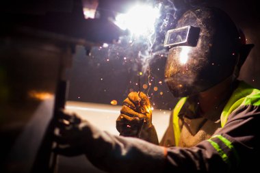 İnsan kaynak yapmak için elektrikli kaynak makinesi kullanarak metal kaynaklama çeliği üzerinde çalışır..