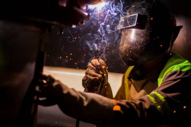 İnsan kaynak yapmak için elektrikli kaynak makinesi kullanarak metal kaynaklama çeliği üzerinde çalışır..