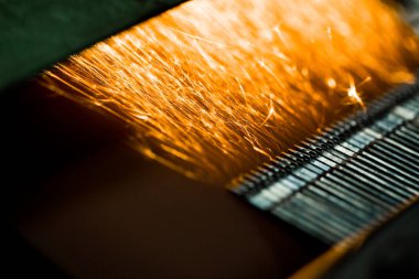 Kıvılcımlar, iğne işleme makinesinde uçuşuyor. Metalürjik bitki arka planı. Endüstriyel üretim kavramı için bitmiş parçalar üretimi. 