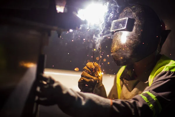 İnsan kaynak yapmak için elektrikli kaynak makinesi kullanarak metal kaynaklama çeliği üzerinde çalışır..