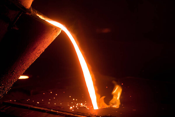 Hot metal is poured from the bowl into a special form in a steel factory. 