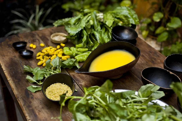 Amazonian cuisine. Green ingredients, manioc soup on a wooden table set. High quality photo